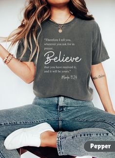 a woman sitting on top of a chair wearing a t - shirt that says believe