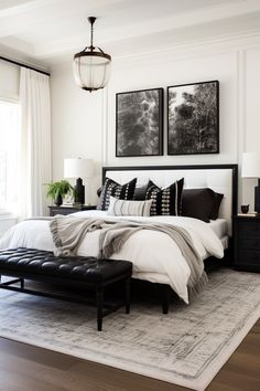 a bedroom with white walls, black and white bedding and pictures on the wall