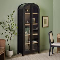 a room with green walls and a black china cabinet in the corner next to a chair