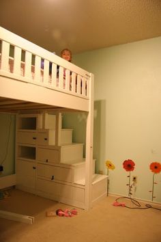 a child is sitting on top of a bunk bed in a room with carpeted flooring