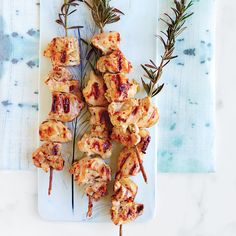 chicken skewers on a plate with rosemary sprigs