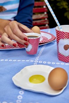 a table topped with plates and cups filled with food next to an egg on a plate