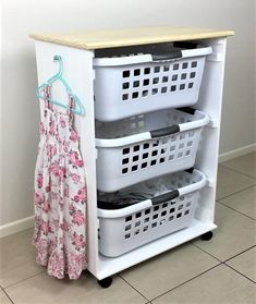 the laundry hamper has three baskets on it and is next to a coat rack