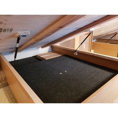 an attic with carpeted flooring and wooden beams