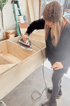 a woman is sanding the floor with an electric sander in her hand and wearing a hat