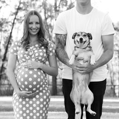 a man and woman standing next to each other holding a dog