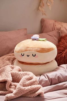 a pillow that looks like a hamburger on top of a bed with blankets and pillows