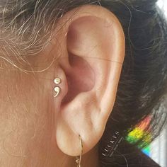 a close up of a person's ear with two small earrings on top of it