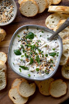 a bowl of dip with bread slices and sprinkles on the side next to it