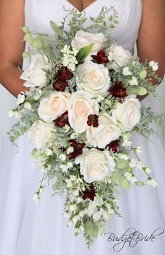 a bridal holding a bouquet of white roses and greenery on her wedding day