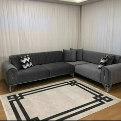 a gray couch sitting on top of a wooden floor next to a white and black rug