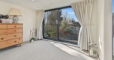 an empty room with a dresser and large window