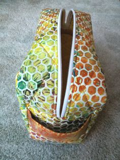 an orange and yellow bag with zippers on the inside, sitting on carpeted floor