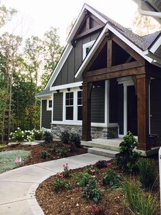 a house that is in the middle of some grass and flowers on the side walk