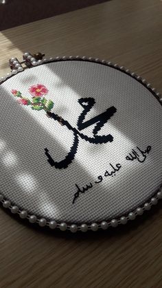 a close up of a cross stitched object on a table with the word love spelled in arabic