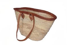 Braided goods from Africa. The bag is handmade from palm fiber, the handles are made from genuine leather. Each part is therefore unique and differs in small features. This basket has two long straps so that it can be carried over the shoulder like a bag.  Dimensions (W x H x D): approx. 54/29 cm x 33 cm x 13 cm, handle length approx. 80 cm  Each product is a unique piece made by hand, that's why isolated deviations and small irregularities are possible and should not be viewed as defects.------ Natural Leather Handwoven Beach Bag, Handwoven Leather Beach Bag In Natural Color, Natural Leather Straw Bag For Market, Brown Straw Bag With Adjustable Strap For Market, Natural Beach Bag With Adjustable Strap For Shopping, Brown Palm Leaf Bag For The Market, Brown Palm Leaf Bag For Market, Brown Palm Leaf Shopping Bag, Brown Palm Leaf Bucket Beach Bag