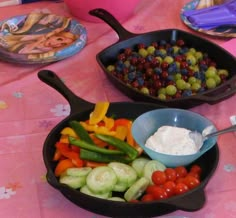 two pans filled with different types of vegetables and dip on top of a table