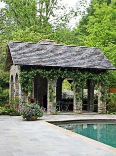 a pool with a gazebo next to it in the middle of a garden area