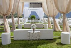 an outdoor wedding setup with white linens and draping on the sidelines