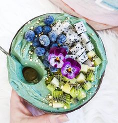 a person holding a bowl filled with fruit and veggies