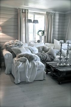 a living room filled with lots of white furniture and pillows on top of each other