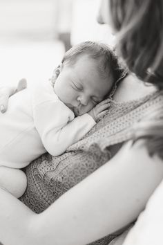 a woman holding a sleeping baby in her arms