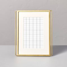 a white and gold frame sitting on top of a table next to a gray wall