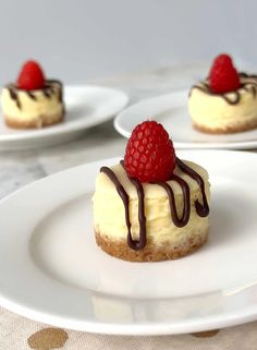 three small desserts with raspberries and chocolate drizzled on them