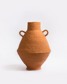 a brown vase sitting on top of a white table