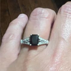 a woman's hand with a black stone ring on it