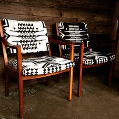 two chairs sitting next to each other in front of a wooden wall with black and white designs on them