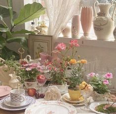 a table with plates, cups and vases filled with flowers on top of it