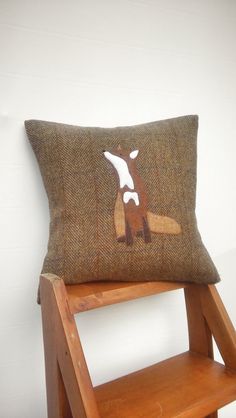 a brown pillow with a white fox on it sitting on top of a wooden chair