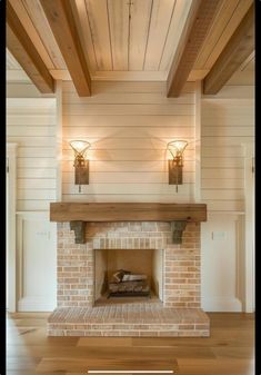 a living room with a brick fireplace and two lights on the wall above it, along with wood flooring