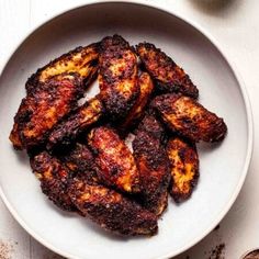 grilled chicken wings on a white plate next to spices