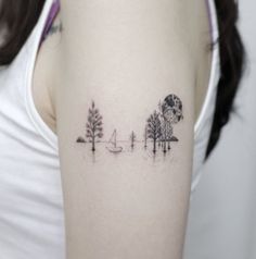 a woman with a tattoo on her arm that has trees and boats in the water