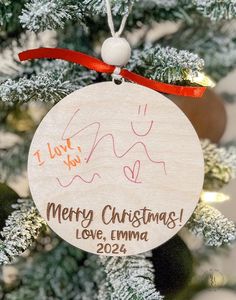 a christmas ornament hanging from the top of a tree with writing on it