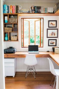 a laptop computer sitting on top of a wooden desk next to a book shelf filled with books