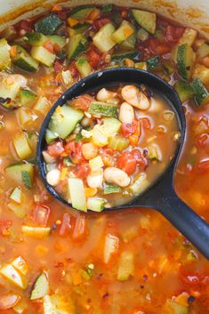 a spoon full of vegetable soup with zucchini, tomatoes and other veggies