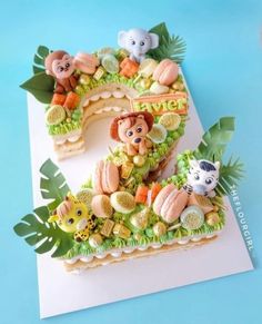 a cake shaped to look like the number one with animals and plants around it on a blue background