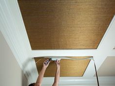 a woman is painting the ceiling with roller shades