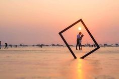 two people standing in the middle of an empty beach at sunset with their arms around each other