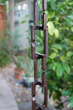 the rain is falling down on some kind of metal sculpture in front of a house