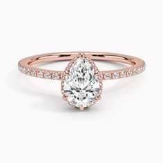 a rose gold engagement ring with a pear shaped center stone and pave set diamonds