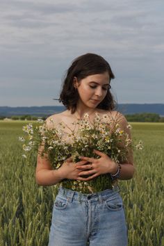 a woman standing in the middle of a field with daisies on her chest and arms