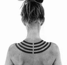 the back of a woman's neck with tattoos on her upper and lower half