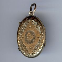 "This Victorian era locket pendant has an enamel design on one side and an ornate engraved design with a leaf in the center on the other side. Measures approximately 1-3/4\" including the loop and just the locket measures approximately 1-7/16\" by 7/8\". Weighs 12.1 grams. Has the original photo covers. Good condition with the slightest bit of wear on the enamel." Victorian Stamped Gold Jewelry, Antique Etched Oval Locket Necklace, Antique Engraved Oval Locket Necklace, Antique Etched Locket Necklace For Memorial, Vintage Etched Oval Pendant Locket Necklace, Antique Filigree Medallion Locket Necklace, Antique Etched Medallion Locket Necklace, Antique Stamped Pendant Jewelry, Antique Etched Pendant Locket Necklace