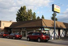 several cars are parked in front of a small restaurant on the side of the road