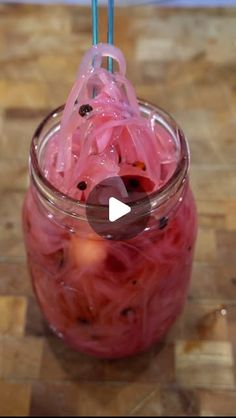 a glass jar filled with red liquid on top of a wooden table