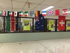 the flags are hanging from the ceiling in this classroom area, and on the wall is a bulletin board with information about different countries